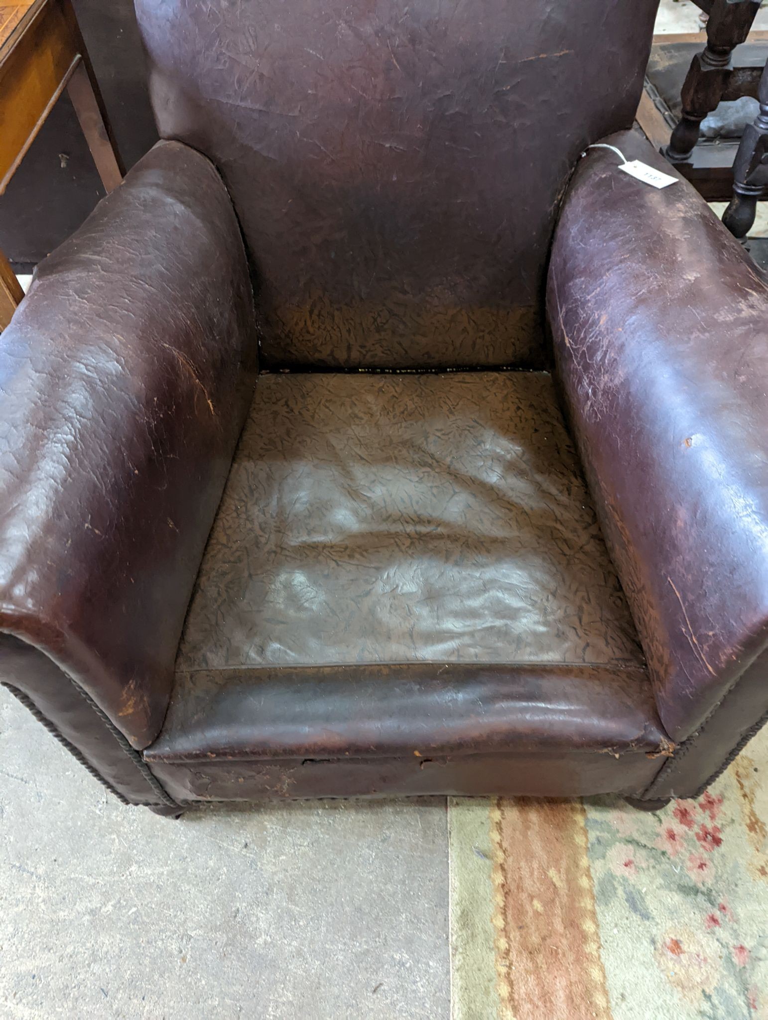 A studded brown leather club armchair, width 86cm, depth 81cm, height 90cm